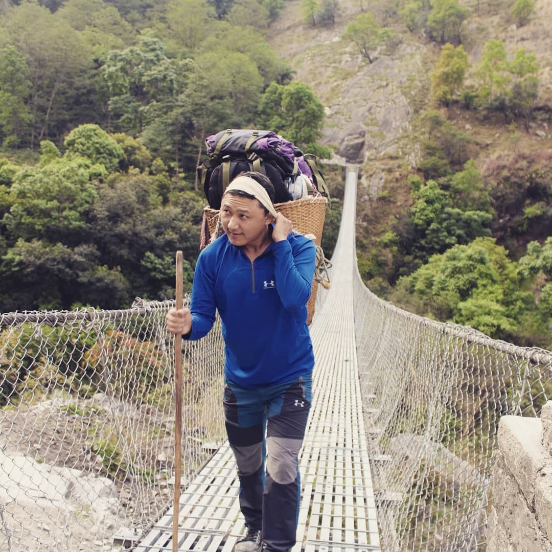 Crossing the suspension bridge carrying a traditional bamboo basket on the way to Lapa village of Dhading district, while working for an INGO. Dhading, 2018 © Saurav Nepal 1._Karma_Chandra_Budha_NEPAL.jpg